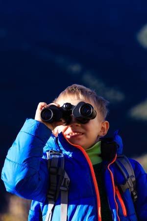 a boy watching view with binoculars during hiking